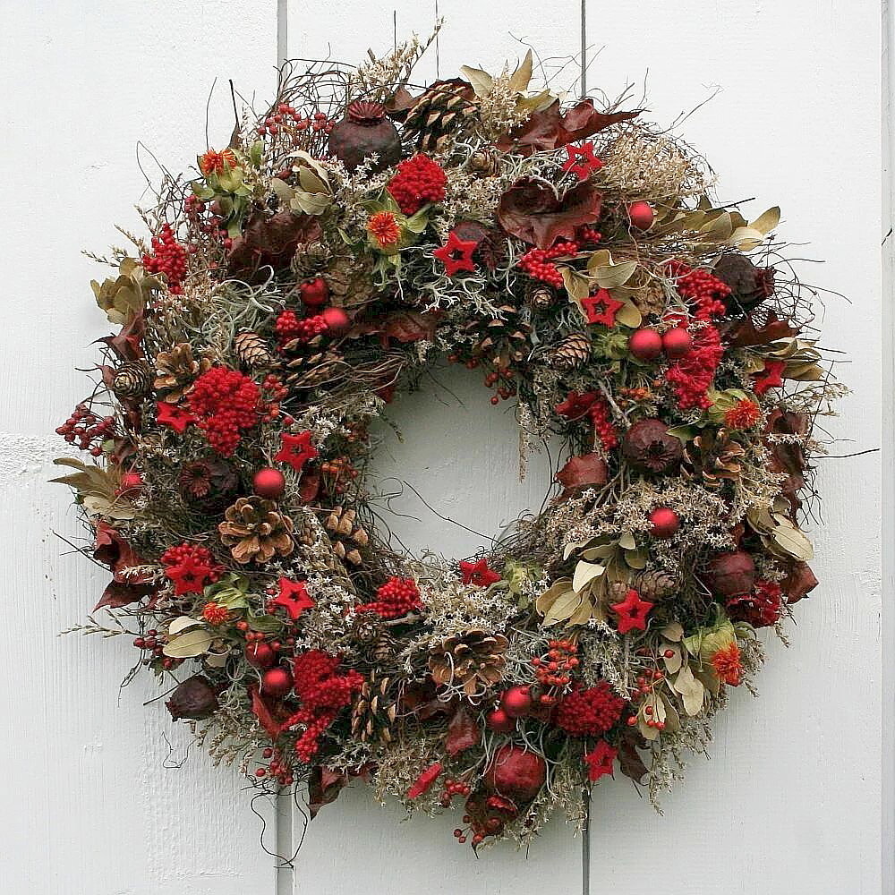 Adventskranz aus Naturmaterialien in warmen Rottönen
