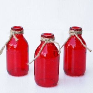 Rote Glasflaschen mit Juteschnur als Tischdeko für...